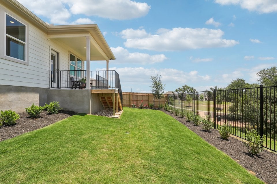 A house with a fence and a lawn in front of it.