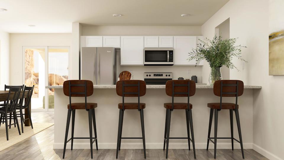 Kitchen with white cabinets, granite countertops, and room for bar seating. 